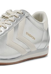 Srebrne i białe sznurowane sneakersy z brandingiem "STADION" i wzorem w zygzak z boku, z brązową gumową podeszwą.