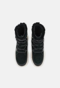 Svarta mocka höga stövlar med fuskpälskrage, med texturerade snören, metallögon och kontrasterande vita gummisulor.