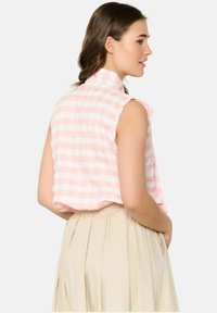 Bez piedurknēm, ar apkakli, blūze ar rozā un baltām svītrām. Viegls audums ar brīvu piegriezumu, savienota ar plīvētu bēšas krāsas svārku.