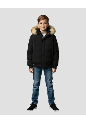 Schwarze gesteppte Jacke mit einem Kunstpelzkapuze, Reißverschlusstaschen und Druckknopfverschluss, kombiniert mit blauen Jeans und schwarzen Schuhen.