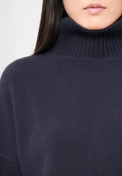 Navy turtleneck sweater with ribbed texture, featuring a high collar and dropped shoulders, made from a soft knit material.