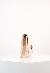 Rosa läderhandväska med kedjestropp, rektangulär form och en grå rosettaccent. Slät textur och detaljer i guldton.