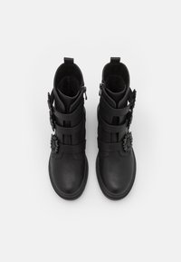 Stivali neri alla caviglia in pelle con una finitura liscia, dotati di cinturini decorativi e un accento floreale sul lato. Chiusura con cerniera sul retro.