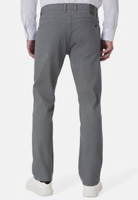 Graue Baumwollhose mit geradem Bein, ausgestattet mit zwei Gesäßtaschen und einem sichtbaren Markenetikett am Bund. Kombiniert mit weißen Schuhen.