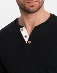 Man i en svart henleytröja med tre synliga träknappar och en vit infodring vid halslinningen.