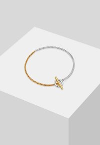 Két színű karkötő, amely egy csavart aranyláncból és egy ezüstláncból áll, középen kör alakú záródással. Sima felület.