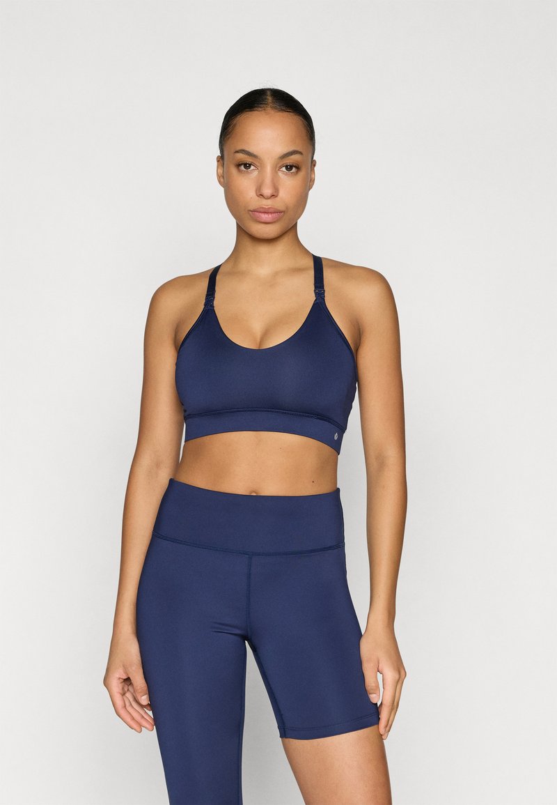 Granatowy sportowy biustonosz z głębokim dekoltem i regulowanymi ramiączkami, w komplecie z dopasowanymi, wysokim stanem spodenek. Gładka faktura, bezszwowa konstrukcja.