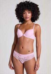 Reggiseno rosa con pizzo e mutandine coordinate, caratterizzati da un tessuto morbido, spalline regolabili e un fiocco decorativo sul davanti.