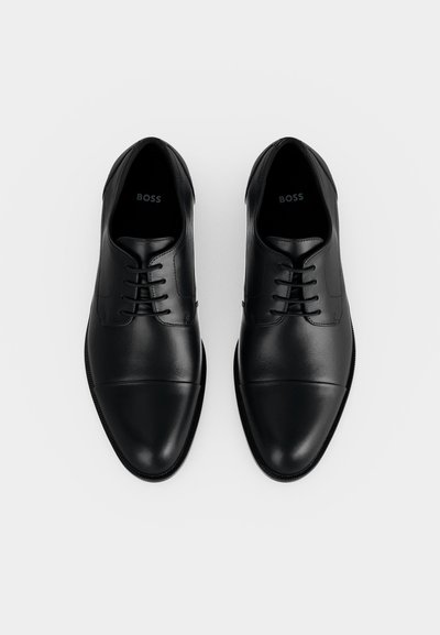 Paire de chaussures habillées en cuir noir poli à lacets avec un détail bout droit, vues de dessus sur fond blanc uni.