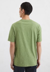 Green striped short-sleeve t-shirt made from a soft fabric, featuring a round neckline and a straight fit with a hem that falls below the waist.