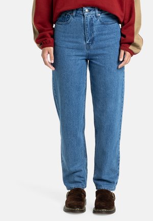 Hoge taille blauwe spijkerbroek met een rechte pijp, vervaagde textuur en zijzakken. Gemaakt met bruine suède instappers.