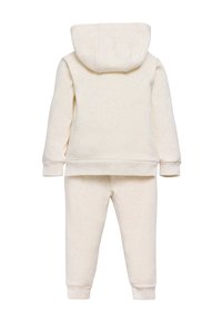 Conjunto de sudadera y pantalones coordinados para niño pequeño de color crema, mostrado desde atrás, con puños y cinturilla acanalados.