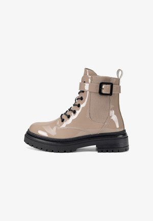 Beżowy lakierowany botek z czarnymi sznurówkami, gumową podeszwą, elastycznym panelem bocznym, regulowanym paskiem z klamrą oraz pętelką do zakładania.