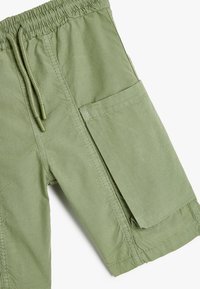 Khaki zielone szorty wykonane z lekkiego materiału, z elastycznym pasem i sznurkiem oraz wyrazistym detalem bocznej kieszeni.