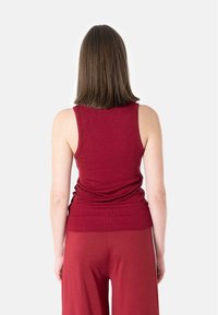Ribbet, ermeløs tanktop i burgunder, kombinert med matchende bukser. Toppen har en tettsittende design og glatt tekstur.