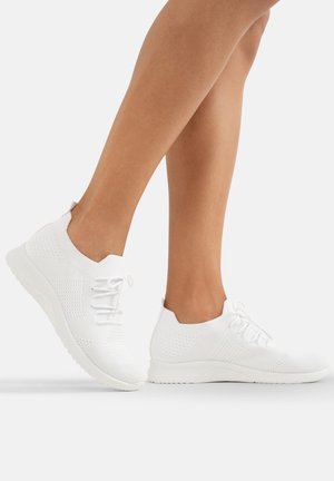 Weiße gestrickte Sportschuhe mit einer texturierten Oberseite, leichtem Sohlen und Schnürverschluss. Sie verfügen über eine abgerundete Zehenpartie und ein minimalistisches Design.