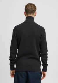 Pulover din tricot ribbed de culoare gri închis, cu guler înalt și mâneci raglan, având un finisaj texturat și manșete ajustate la încheieturi.