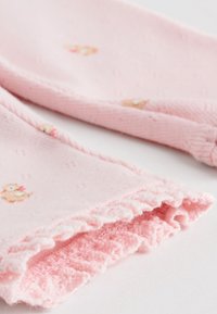 Colanți roz din bumbac cu o textură moale, având un tiv ondulat și imprimeuri mici cu animale. Țesătura prezintă un model subtil și puțină elasticitate.