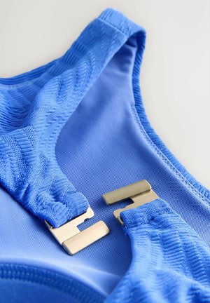 Close-up of blue textured fabric with two silver metal clasps positioned to connect.