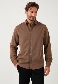 Brun skjorte med knapper, lavet af et struktureret stof, med lange ærmer og spids krave, der har en tætsiddende pasform og en subtil stribe mønster.