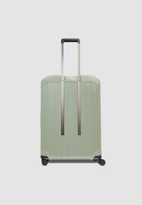 Valise rigide vert menthe avec une texture nervurée verticale, poignée rétractable argentée et roues à la base.