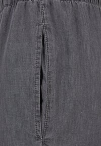 Gray fabric with a textured surface. Features an elastic waistband and a vertical slit on one side, stitched with a contrasting thread.