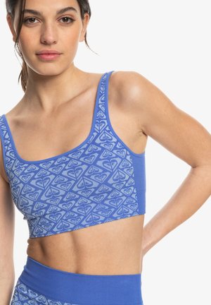 Blue crop top made of soft fabric, featuring a geometric pattern in a lighter shade, with narrow straps and a fitted design.