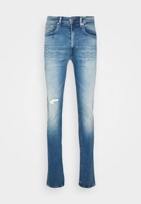 Vaqueros de mezclilla azul descolorida con corte recto, que presentan un agujero rasgado en la rodilla derecha y un sutil efecto de desgaste alrededor de la cintura.