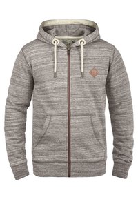 Sudadera con capucha gris con cremallera y acabado texturizado, con capucha forrada, cremallera marrón y un pequeño parche de cuero en el pecho. Incluye bolsillos delanteros.