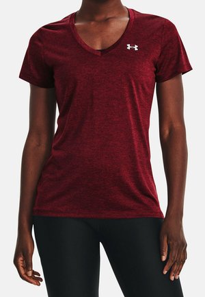 Frau trägt ein dunkelrotes sportliches T-Shirt mit V-Ausschnitt und kurzen Ärmeln sowie einem kleinen weißen Under Armour-Logo auf der Brust.