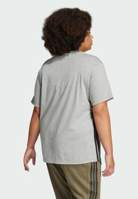 Gray cotton t-shirt with short sleeves, a relaxed fit, and black side stripes. The back view shows a simple, seamless design.