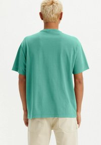 Turquoise cotton t-shirt with a crew neck and short sleeves, viewed from the back. Smooth texture, relaxed fit, no additional patterns or accents.