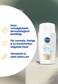 Weiße zylindrische Sonnencremeflasche mit einem Klappdeckel. Blau-goldene Etikettierung, enthält SPF 50+, leichte, nicht komedogene Formel.