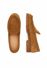 Brązowe zamszowe mokasyny o jednolitej konstrukcji, okrągłym nosku i teksturowanej gumowej podeszwie. Cholewka zdobiona jest przeszyciami i gładką skórzaną podszewką.