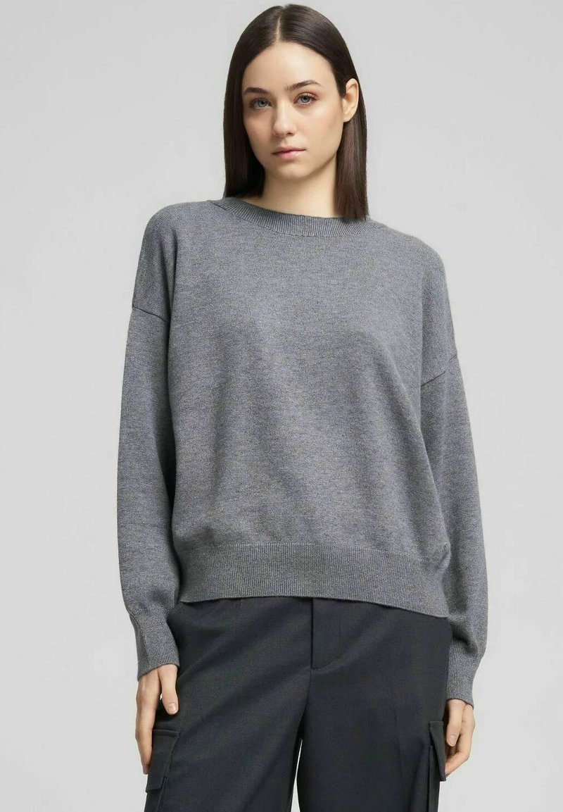 Maglione grigio lavorato a maglia con scollo rotondo, spalle scivolate e orlo a coste. Il tessuto è morbido con una texture liscia e vestibilità rilassata.