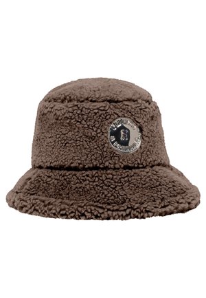 Brown fluffy bucket hat with round metallic logo badge displaying text and a small bear graphic on the front side.