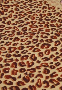 Luipaardprint stof met een beige achtergrond en donkerbruine en roestkleurige vlekken in verschillende maten, met een zachte, gestructureerde uitstraling.