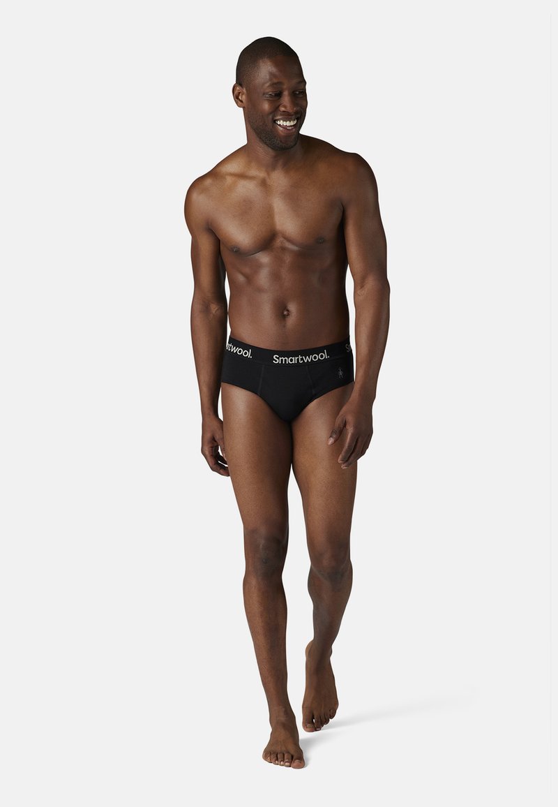 Caleçons noirs en tissu doux, dotés d'une large ceinture avec le texte "Smartwool". Le design est ajusté et présente une texture lisse.