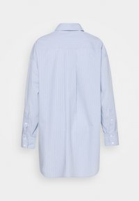 Light blue long-sleeve shirt with vertical white and dark blue pinstripes, buttoned cuffs, and a back yoke seam, shown from the back.