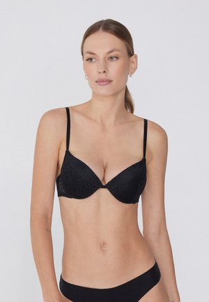 Reggiseno in pizzo nero con coppe imbottite e spalline regolabili, caratterizzato da un motivo sottile e un design con scollatura profonda.