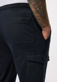 Marine cargobroek met elastische tailleband, enkele achterzak en zijzak. Zachte, gladde stof met een stevige textuur.