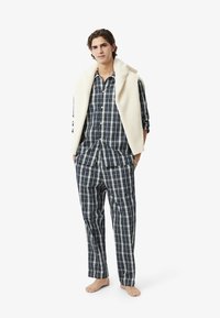 Set di pigiama a quadri in navy, verde e crema, composto da una camicia con bottoni e pantaloni larghi, completato da un gilet in maglia testurizzata crema.