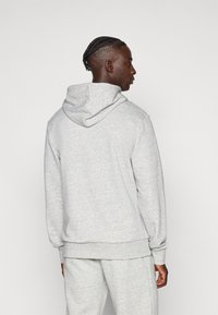 Γκρι φούτερ με κουκούλα από μαλακό ύφασμα, με χαλαρή εφαρμογή, ριμπ μανσέτες και μεσαίου μεγέθους κουκούλα, εμφανιζόμενο από πίσω.