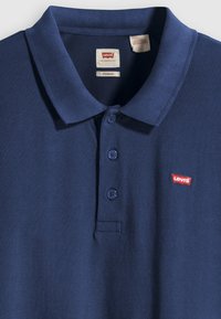 Polo azul-marinho em tecido texturizado, com pala de dois botões e um pequeno logótipo vermelho da Levi's no lado esquerdo.