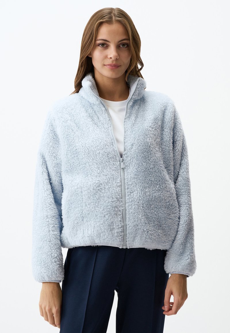 Giacca in pile azzurro chiaro con colletto alto, chiusura con zip e texture morbida. Presenta maniche larghe e una vestibilità comoda.