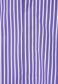 Lila och vit randig tyg har smala vertikala linjer, en slät textur och noggrant söm längs sömmen.