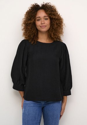 Black textured blouse with three-quarter puff sleeves and a rounded neckline, paired with light blue jeans.