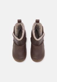 Bottines en cuir marron avec une doublure en fourrure douce, bout arrondi et détails cousus. Elles disposent d'une languette pour un enfilage facile.