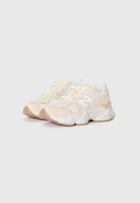 Par de sapatilhas New Balance em bege e branco com detalhes em malha e camurça sobre fundo branco, ângulo à esquerda.