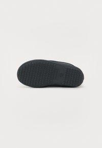 Semelle de chaussure bleu foncé avec une surface en caoutchouc texturée, présentant un motif en zigzag pour l'adhérence et un logo intégré dans la zone du talon.
